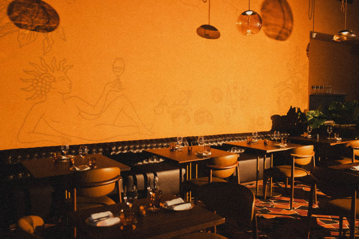 The dining room, wide — mural wall and banquette tables